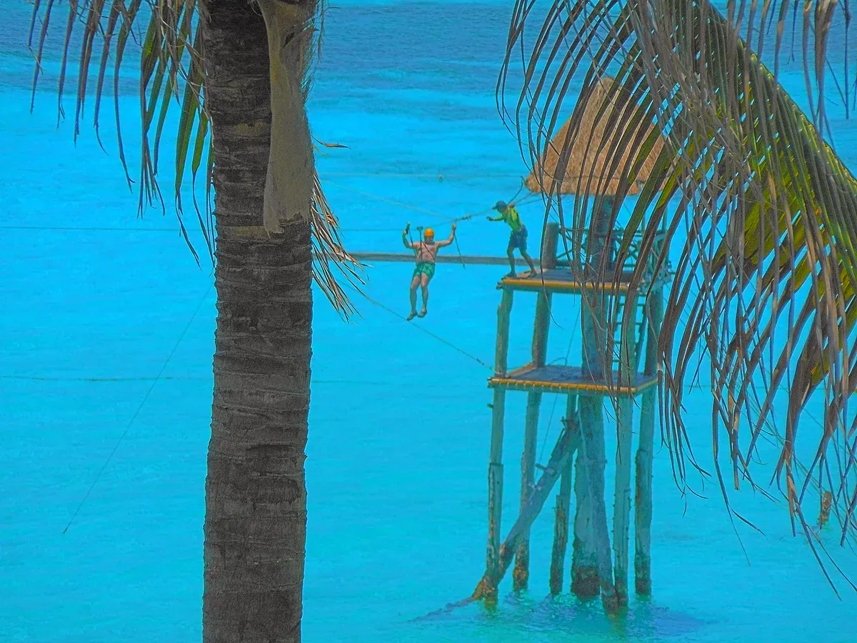 Zip line over turquoise water at Garrafon Natural Reef Park near Punta Sur, Isla Mujeres, on a Cancun yacht rental route