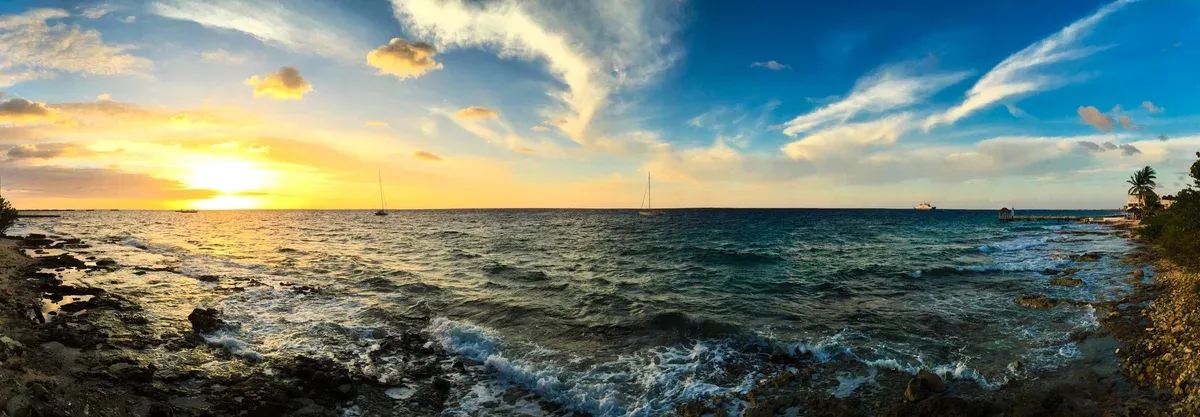 Golden sunset over rocky Caribbean shore and open sea near Cancun for a Cancun yacht rental trip