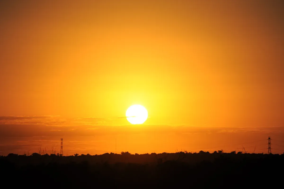 Orange sun setting over the Cancun shoreline at the time of a Cancun sunset cruise