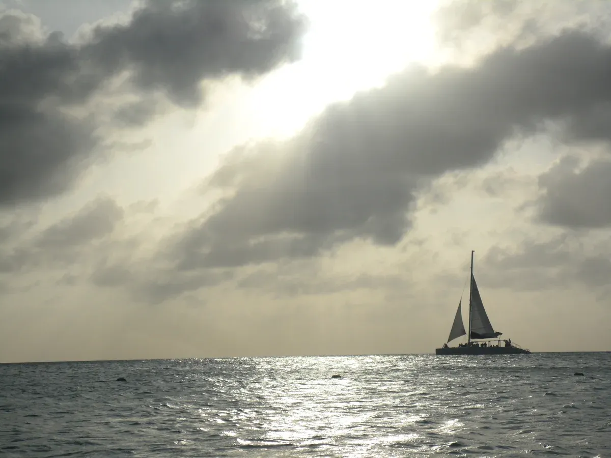 A sailing catamaran on open Caribbean water under a cloudy evening sky, typical of a Cancun sailing tour